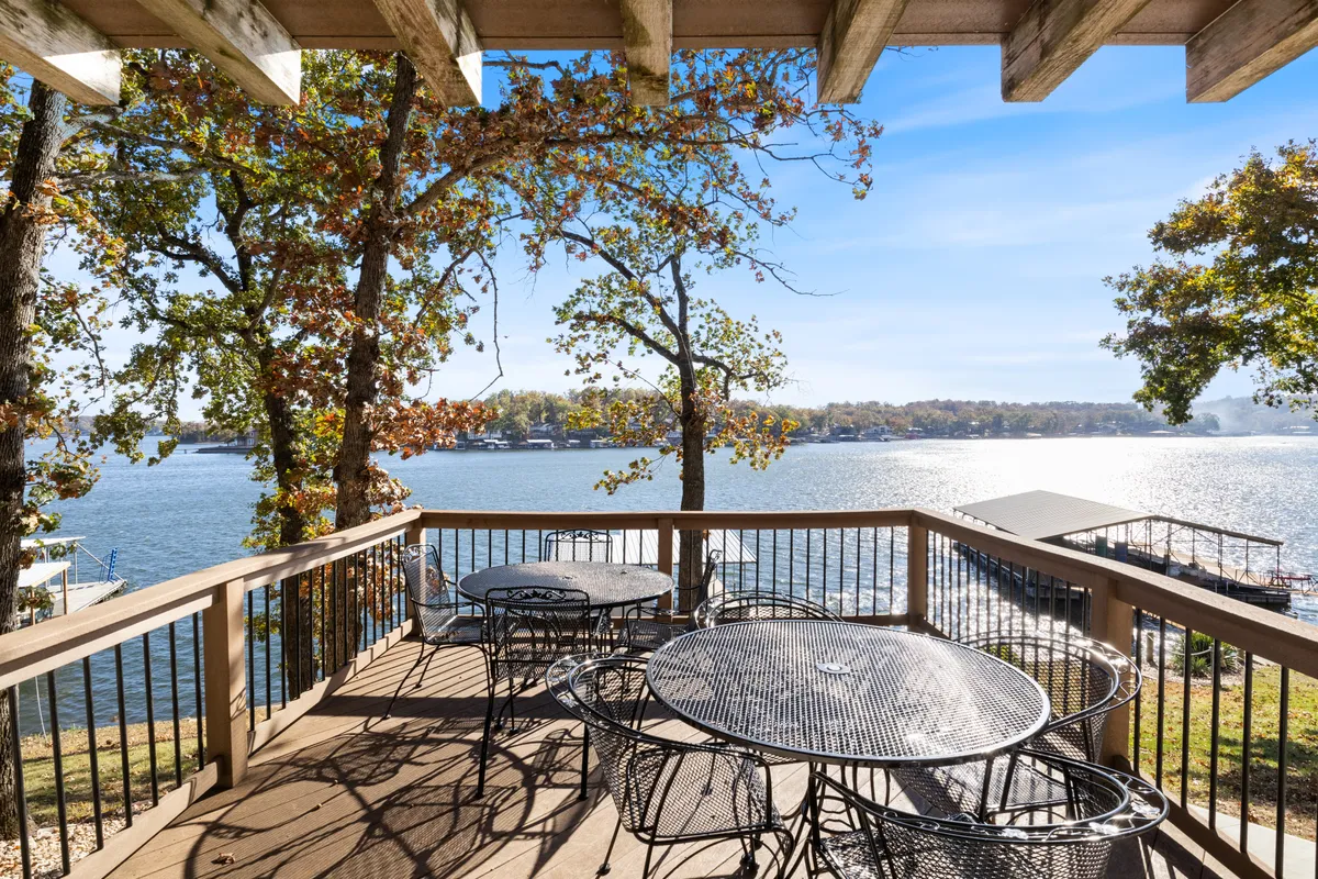 This exterior image features an expansive water view with outdoor seating nestled among surrounding trees. The tranquil lakeside setting is ideal for relaxing, socializing, or enjoying nature, with ample space for gatherings and group activities.