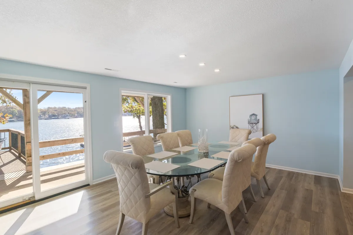 A dining area featuring a large table surrounded by chairs, next to expansive windows that look out onto the lake. The ambiance is warm and welcoming, ideal for group meals, gatherings, or simply enjoying scenic breakfasts with loved ones.