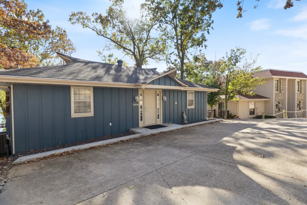 This exterior shot highlights the blue exterior of the house, framed by mature trees and a welcoming front door. The surrounding greenery and the inviting porch hint at outdoor activities and relaxation opportunities.